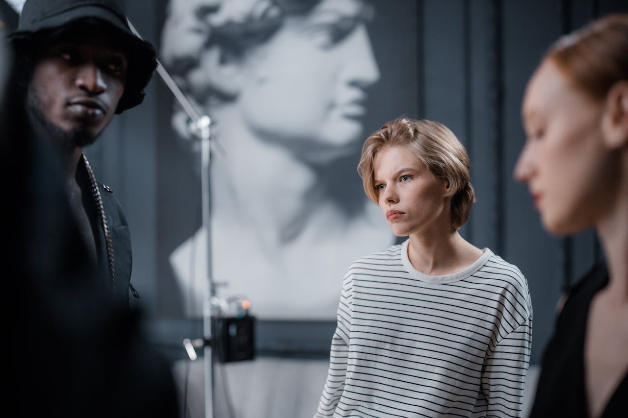 services-03 Three models in a fashion photoshoot with blurred classical sculpture background in a studio.